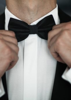 Man fies black bow tie on white shirt