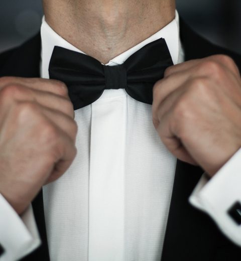 Man fies black bow tie on white shirt
